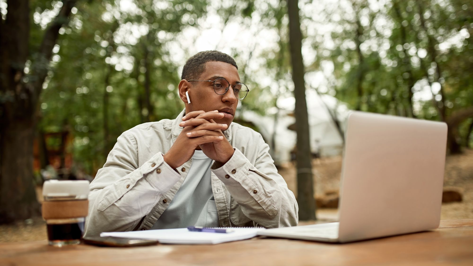  A person sitting outdoors staring at a laptop screen.