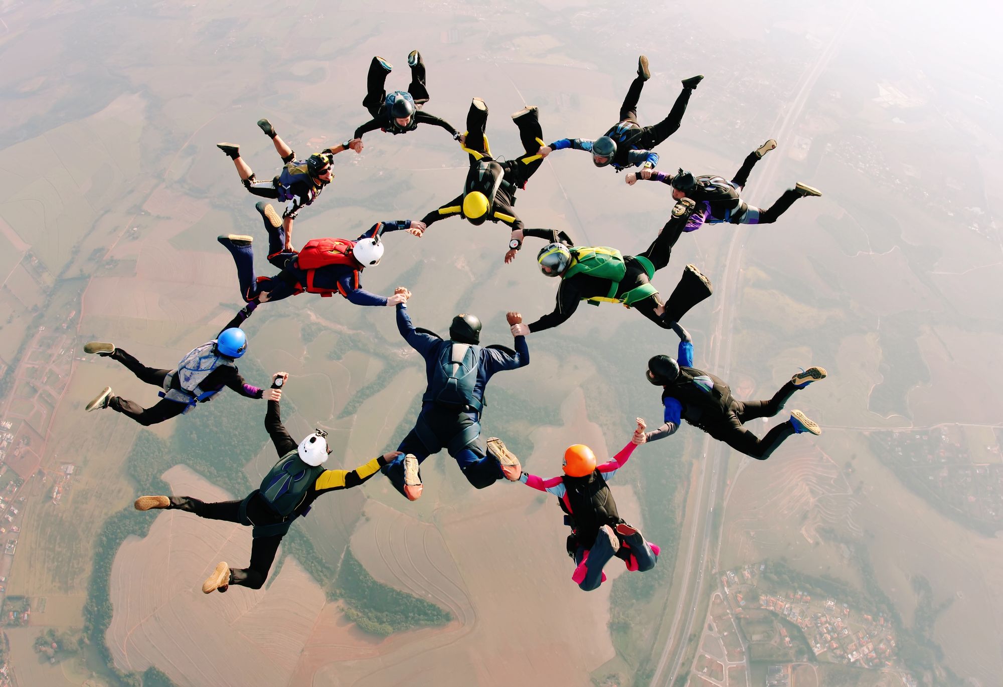 Skydivers holding hands making a formation. High angle view.