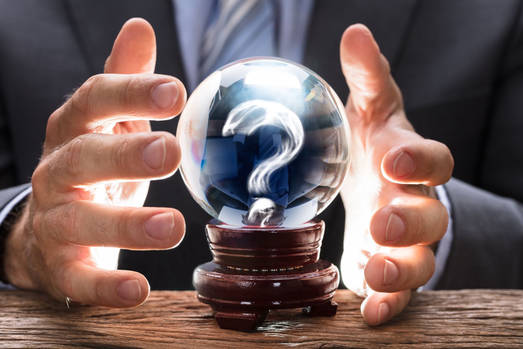 Businessman covering crystal ball with question mark