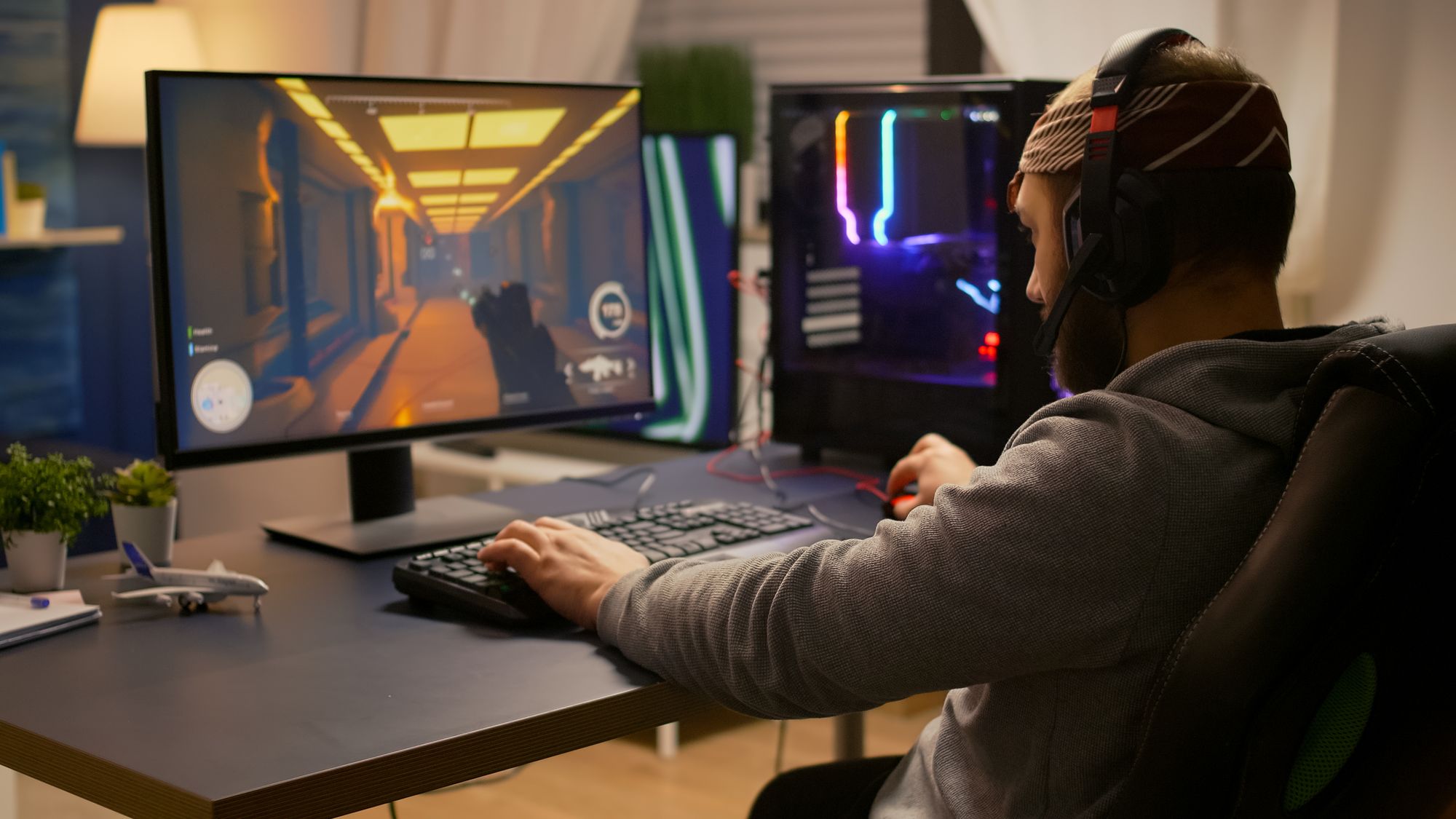 Person sitting at a desk playing a first-person shooting video game.