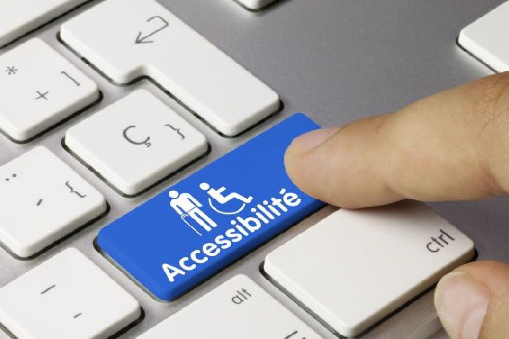 Un doigt appuyant sur la touche bleue du clavier appelé « Accessibilité ». 