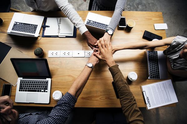  Les membres d’une équipe joignent leurs mains au-dessus d’un bureau.