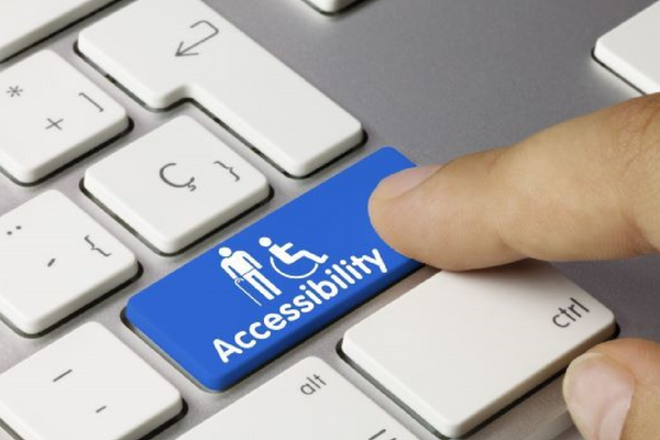 A finger pressing on blue keyboard button labelled “Accessibility”.